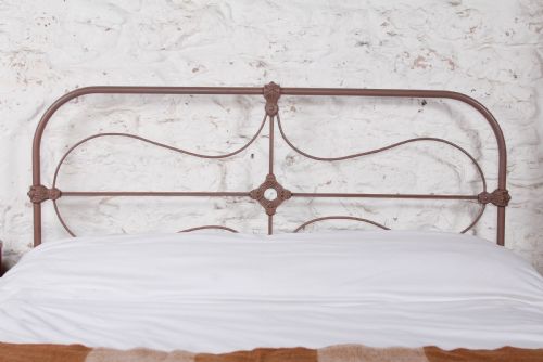 fig 2. An antique Irish double bed frame constructed from painted iron with curved metal scrollwork and decorative cast medallions.