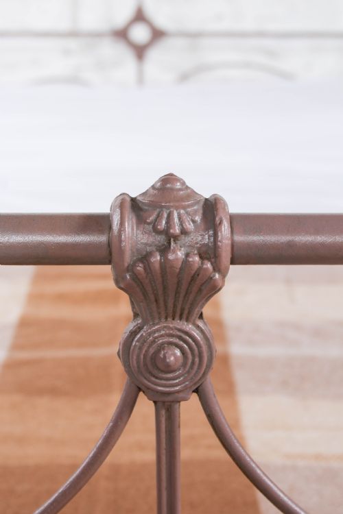 fig 3. An antique Irish double bed frame constructed from painted iron with curved metal scrollwork and decorative cast medallions.