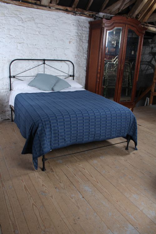 fig 1. A Victorian black iron king-size bedstead featuring a rounded headboard frame decorated with geometric Celtic strapwork and cast iron bosses.