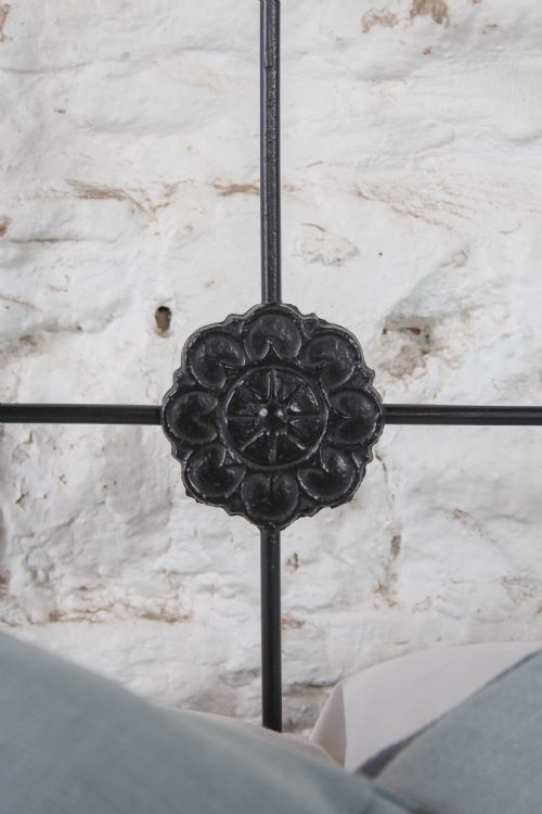 fig 3. A Victorian black iron king-size bedstead featuring a rounded headboard frame decorated with geometric Celtic strapwork and cast iron bosses.