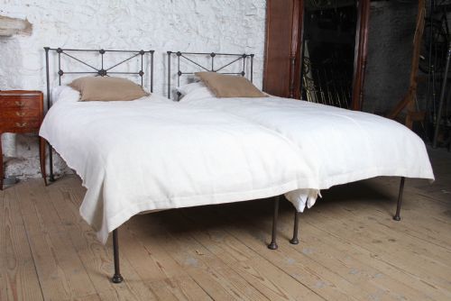 fig 1. A pair of dark Victorian wrought iron single beds with geometric headboards and footless frames.