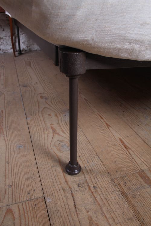 fig 4. A pair of dark Victorian wrought iron single beds with geometric headboards and footless frames.