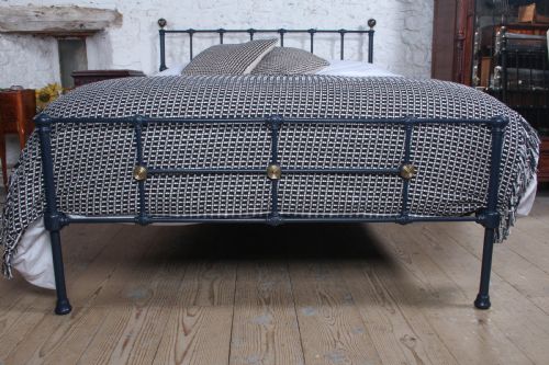 fig 1. A Victorian style king size dark blue cast iron bedstead featuring decorative brass finials and a low footboard.