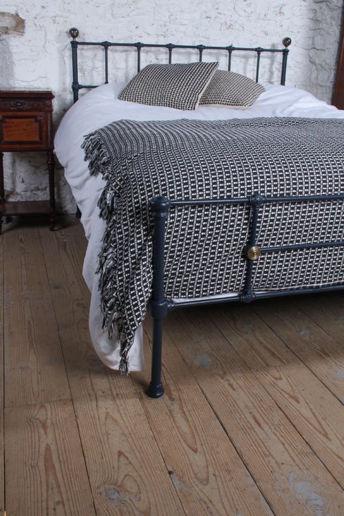 fig 4. A Victorian style king size dark blue cast iron bedstead featuring decorative brass finials and a low footboard.