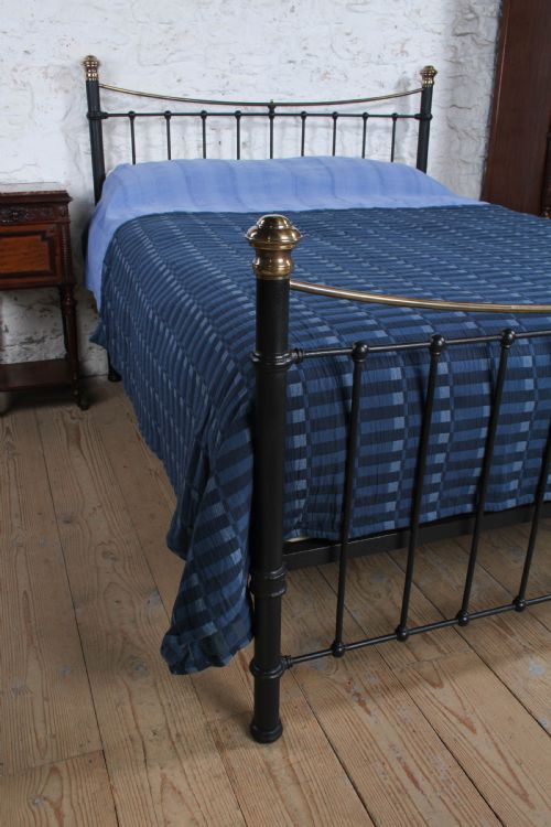 fig 1. An Edwardian black iron and brass king-size bedstead featuring a curved dip rail and brass corner finials.