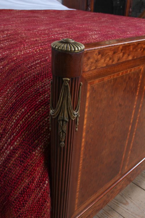 fig 2. An antique French mahogany king-size bed frame featuring inlaid wood borders, decorative brass mounts, and fluted corner posts.