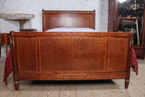 fig 3. An antique French mahogany king-size bed frame featuring inlaid wood borders, decorative brass mounts, and fluted corner posts.