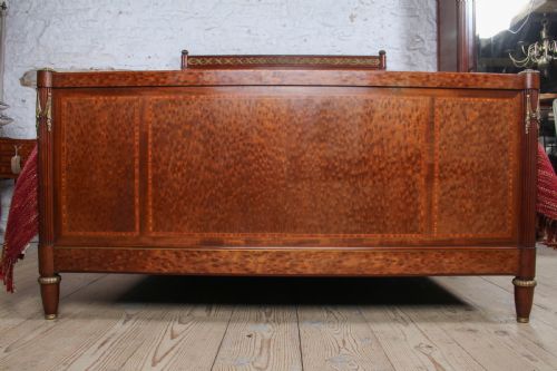 fig 4. An antique French mahogany king-size bed frame featuring inlaid wood borders, decorative brass mounts, and fluted corner posts.