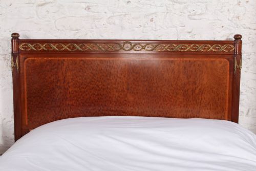 fig 5. An antique French mahogany king-size bed frame featuring inlaid wood borders, decorative brass mounts, and fluted corner posts.