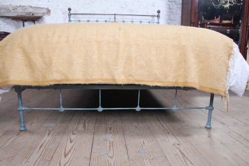 fig 4. A Victorian king-size light blue painted iron bedstead featuring a straight brass top rail with polished brass corner finials.