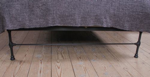 fig 1. A Victorian Art Nouveau style black cast iron king size bed frame featuring vertical spindles and decorative joinery details.