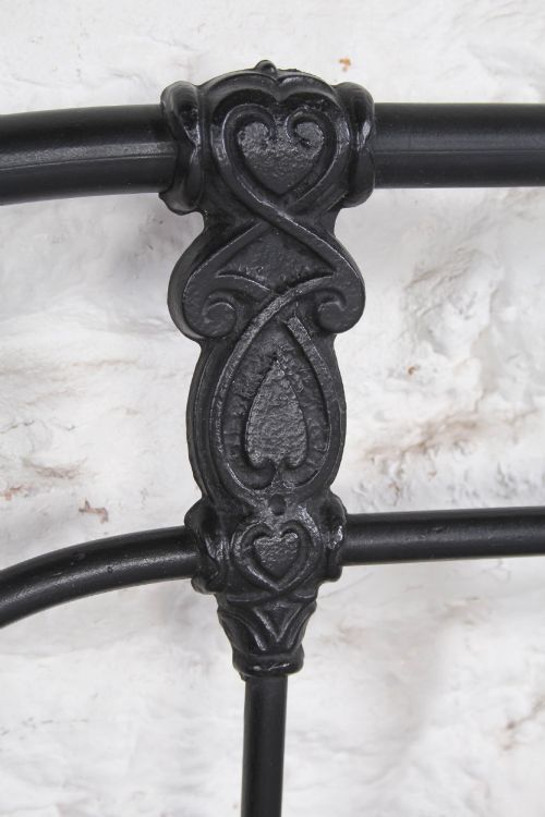 fig 4. A Victorian Art Nouveau style black cast iron king size bed frame featuring vertical spindles and decorative joinery details.
