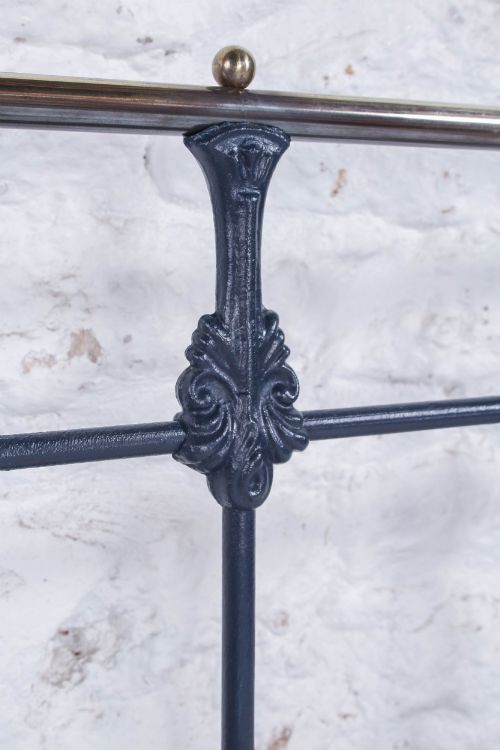 fig 2. A Victorian double bed frame featuring a dark cast iron headboard with vertical spindles and a polished brass top rail with corner finials.