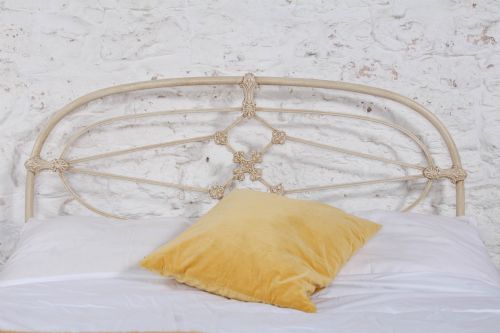 fig 1. A cream-painted Victorian metal double bed frame featuring a arched wrought iron headboard with decorative cast iron joints.