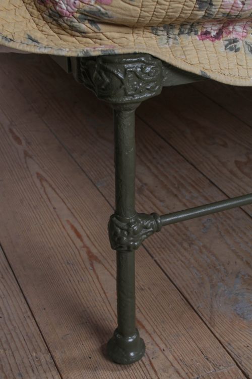 fig 3. Victorian dark green cast iron double bedstead featuring an arched headboard with decorative scrollwork and a low foot end.