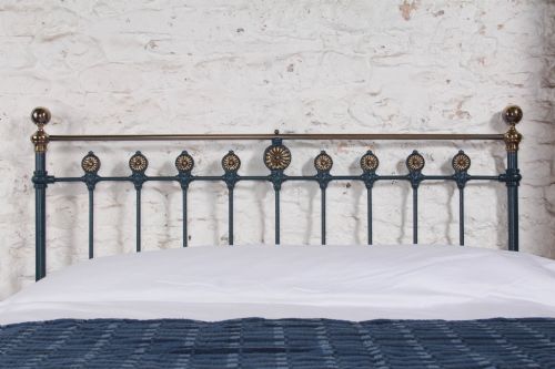 fig 1. A Victorian king size cast iron bedstead with brass top rail and decorative rosettes, dressed in white and dark blue bedding.
