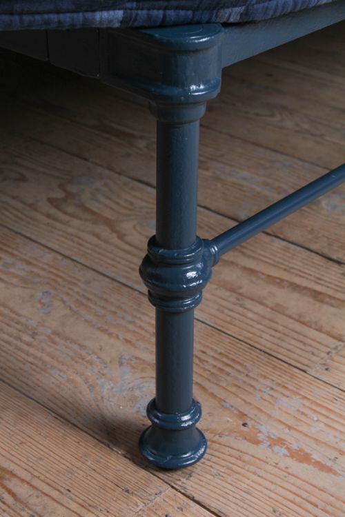 fig 2. A Victorian king size cast iron bedstead with brass top rail and decorative rosettes, dressed in white and dark blue bedding.