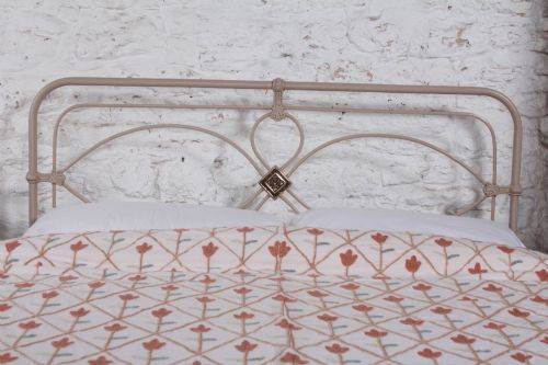 fig 1. A cream painted wrought iron king size bed frame featuring a high arched headboard with central brass detailing and a low foot end.
