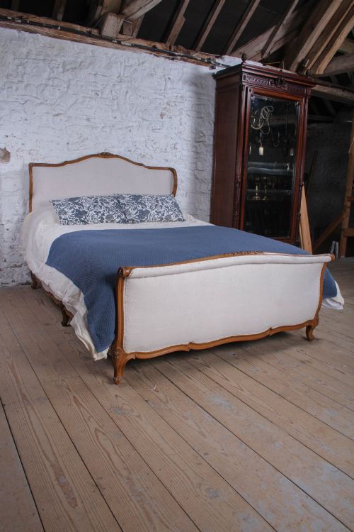 fig 1. A Louis XV style king-size bed frame featuring a carved wooden structure, cabriole feet, and neutral upholstered headboard and footboard panels.