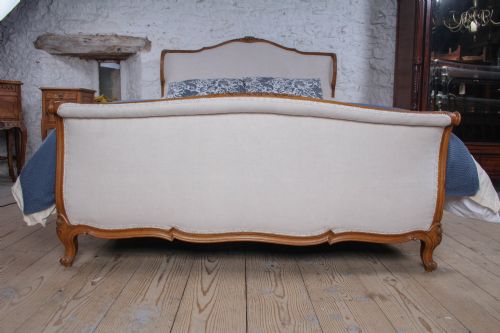 fig 2. A Louis XV style king-size bed frame featuring a carved wooden structure, cabriole feet, and neutral upholstered headboard and footboard panels.