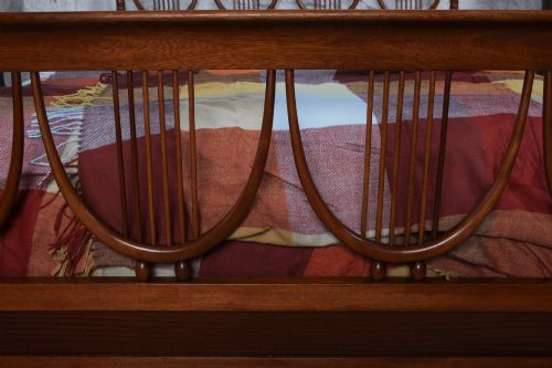 fig 1. A double bed frame constructed from cherry wood featuring curved headboard and footboard panels fitted with vertical spindles.