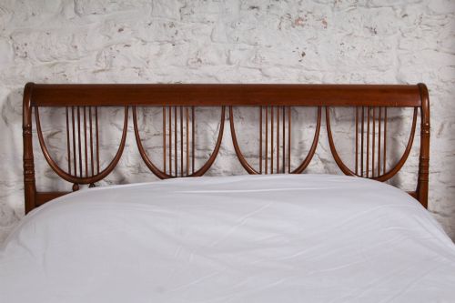 fig 2. A double bed frame constructed from cherry wood featuring curved headboard and footboard panels fitted with vertical spindles.
