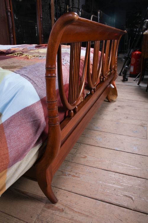 fig 3. A double bed frame constructed from cherry wood featuring curved headboard and footboard panels fitted with vertical spindles.