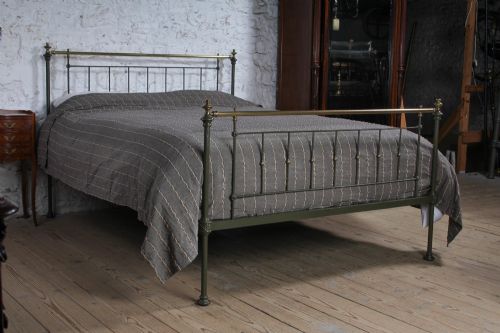fig 1. A dark green painted iron and brass king-size bedstead featuring vertical iron spindles and polished brass top rails.