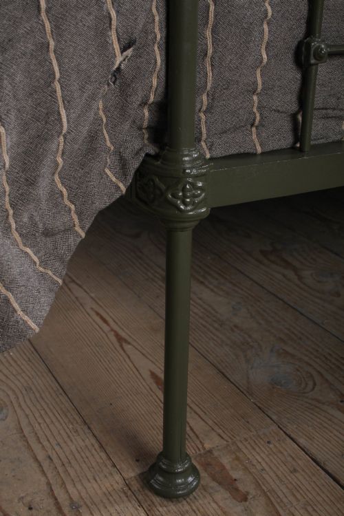 fig 4. A dark green painted iron and brass king-size bedstead featuring vertical iron spindles and polished brass top rails.