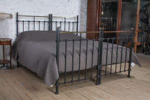 fig 3. A pair of Edwardian black iron single beds featuring square tube framing, vertical spindles, and polished brass top rails.