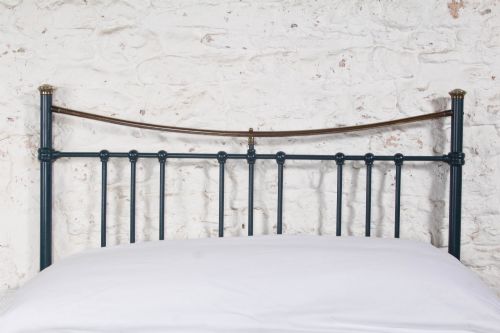 fig 2. An Edwardian dark blue painted iron double bed frame featuring curved brass dip rails, vertical spindles, and ceramic castors.