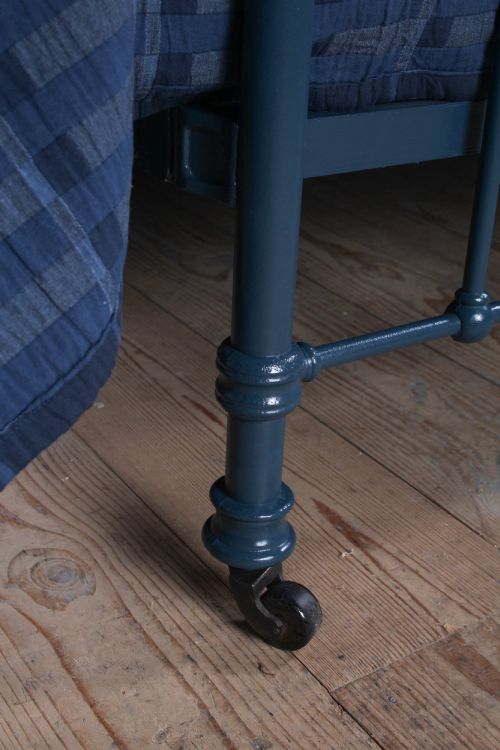 fig 4. An Edwardian dark blue painted iron double bed frame featuring curved brass dip rails, vertical spindles, and ceramic castors.