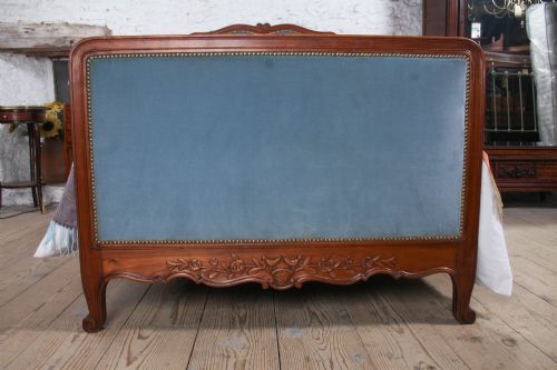 fig 1. A French Provincial style single bed featuring a carved timber frame with blue velvet upholstered headboard and footboard panels.