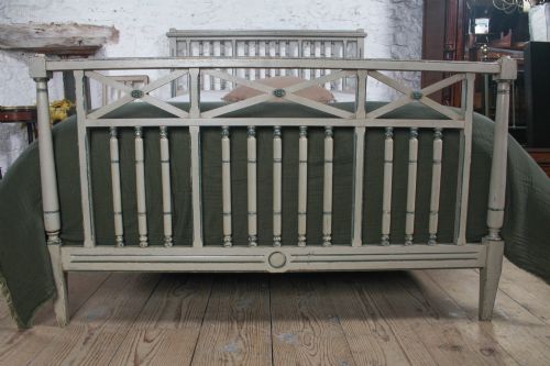 fig 2. A grey painted French Arts and Crafts double bedstead featuring vertical spindle detailing and a patterned footboard.