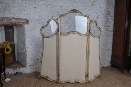 fig 2. A three-panel Louis XV style folding dressing screen featuring carved cream painted timber frames with glass upper apertures and upholstered lower panels.