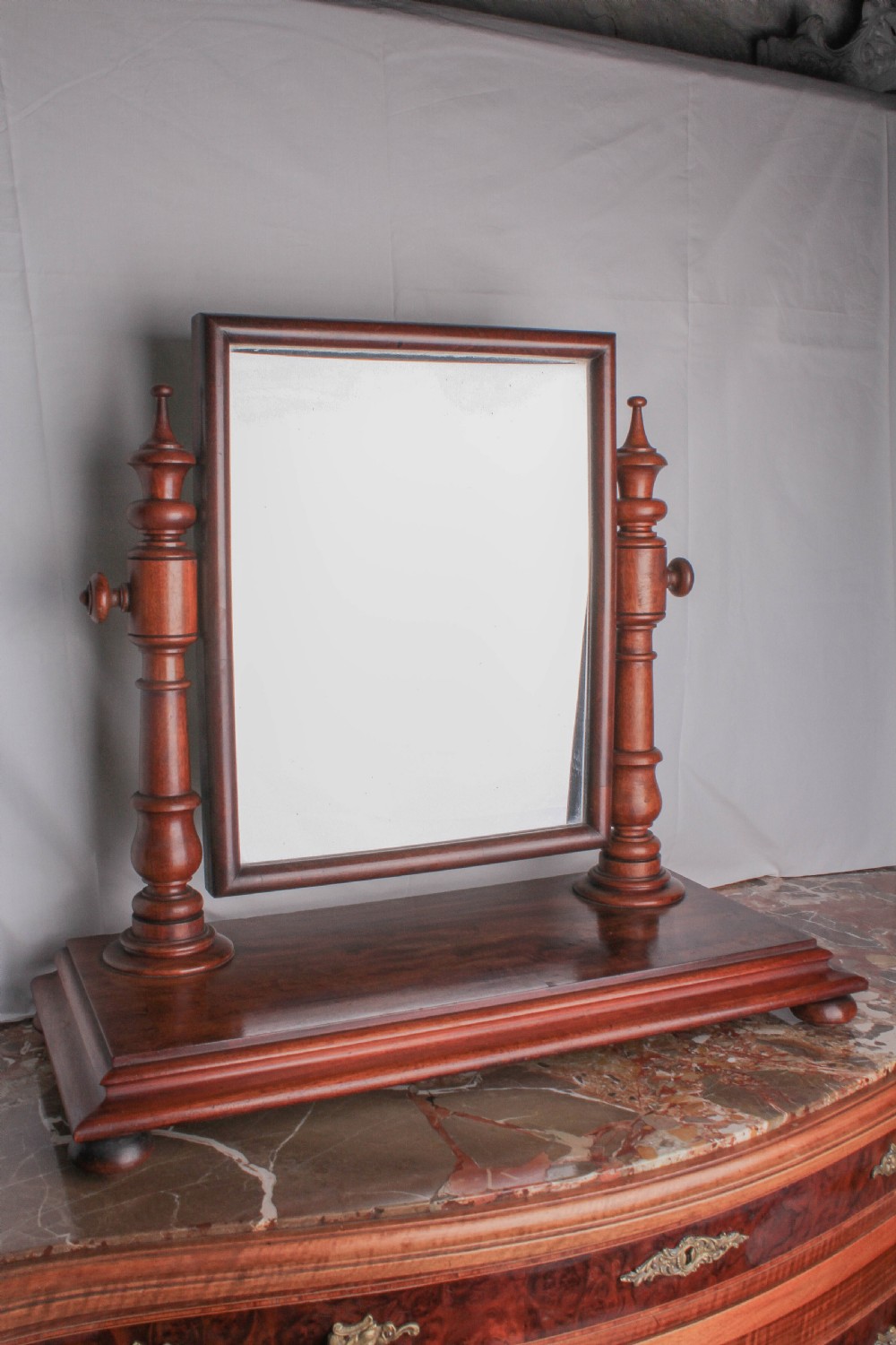 A Victorian mahogany dressing table mirror with turned support columns, finials, and a rectangular timber plinth base.