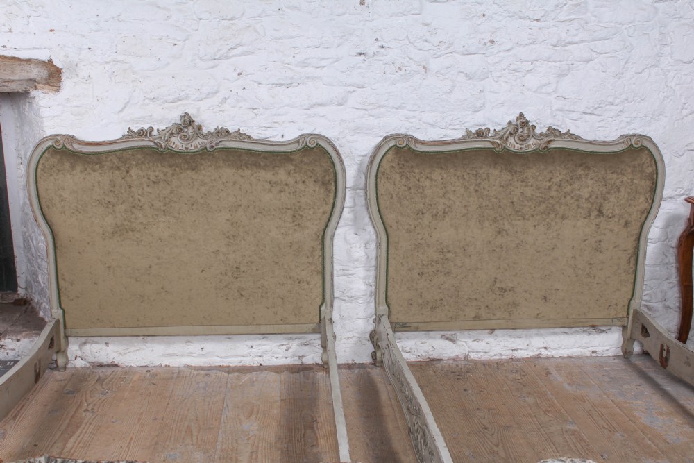 A pair of French Louis XV style single bed frames with carved grey painted timber and olive green velvet upholstered panels. View X