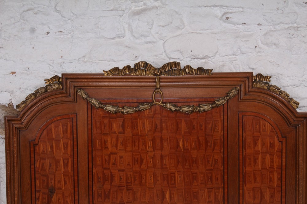 A pair of antique French fruitwood single beds featuring geometric parquetry inlay and decorative gilt bronze mounts on the headboards and footboards. View VI