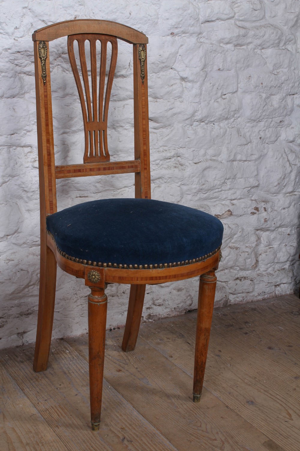 A pair of French Louis XVI style side chairs with inlaid light wood frames, pierced balloon back splats, and circular navy blue velvet upholstered seats. View VIII