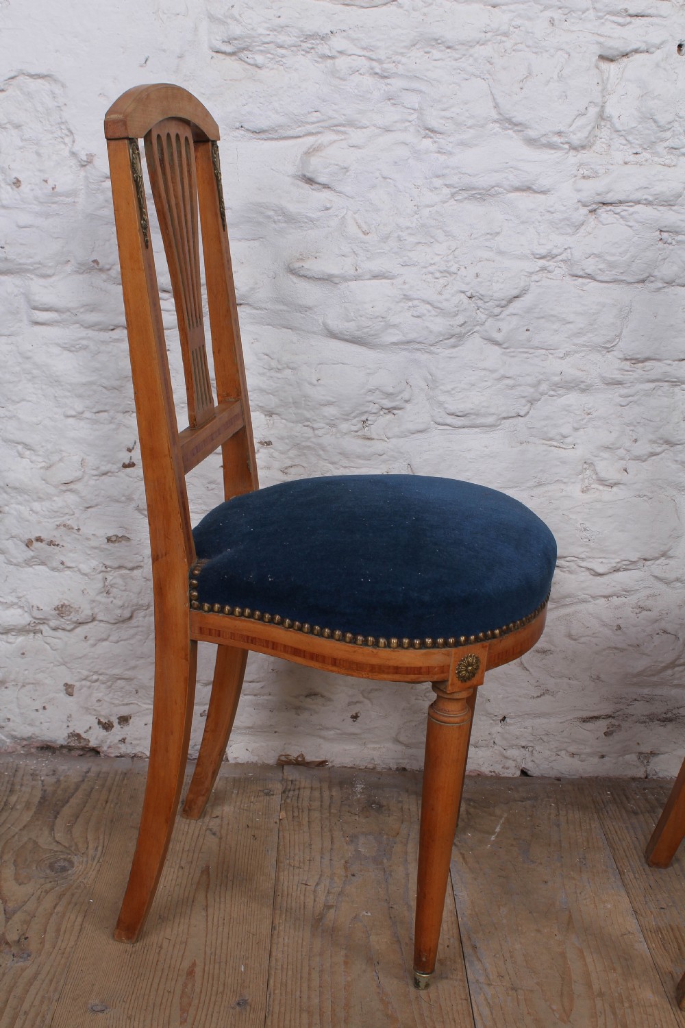 A pair of French Louis XVI style side chairs with inlaid light wood frames, pierced balloon back splats, and circular navy blue velvet upholstered seats. View IX