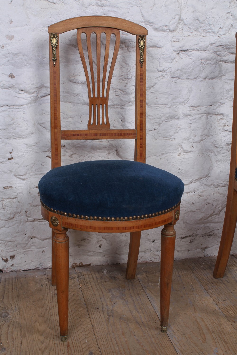 A pair of French Louis XVI style side chairs with inlaid light wood frames, pierced balloon back splats, and circular navy blue velvet upholstered seats. View X
