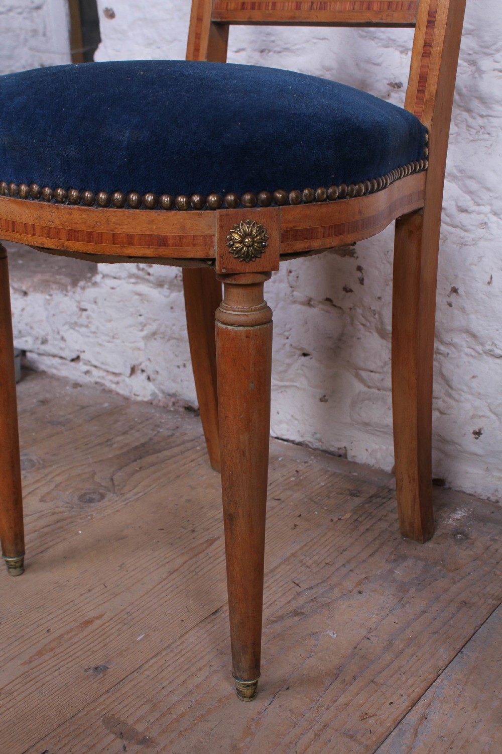 A pair of French Louis XVI style side chairs with inlaid light wood frames, pierced balloon back splats, and circular navy blue velvet upholstered seats. View XII