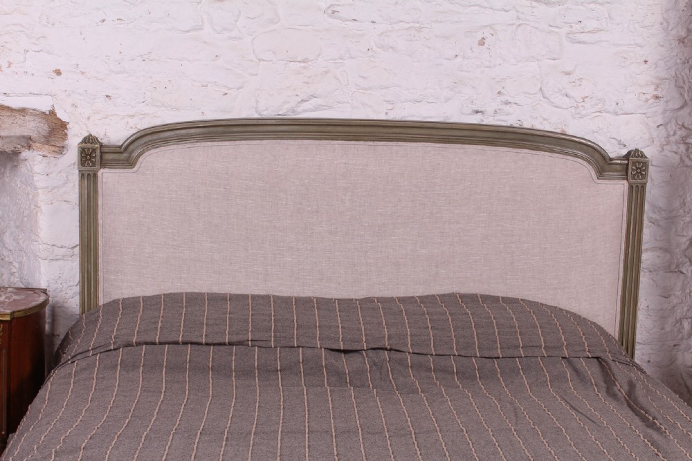 A Louis XVI style French king-size bed frame featuring a muted green painted wooden trim, fluted corner posts, rosettes, and cream linen upholstered panels on the headboard and footboard. View III