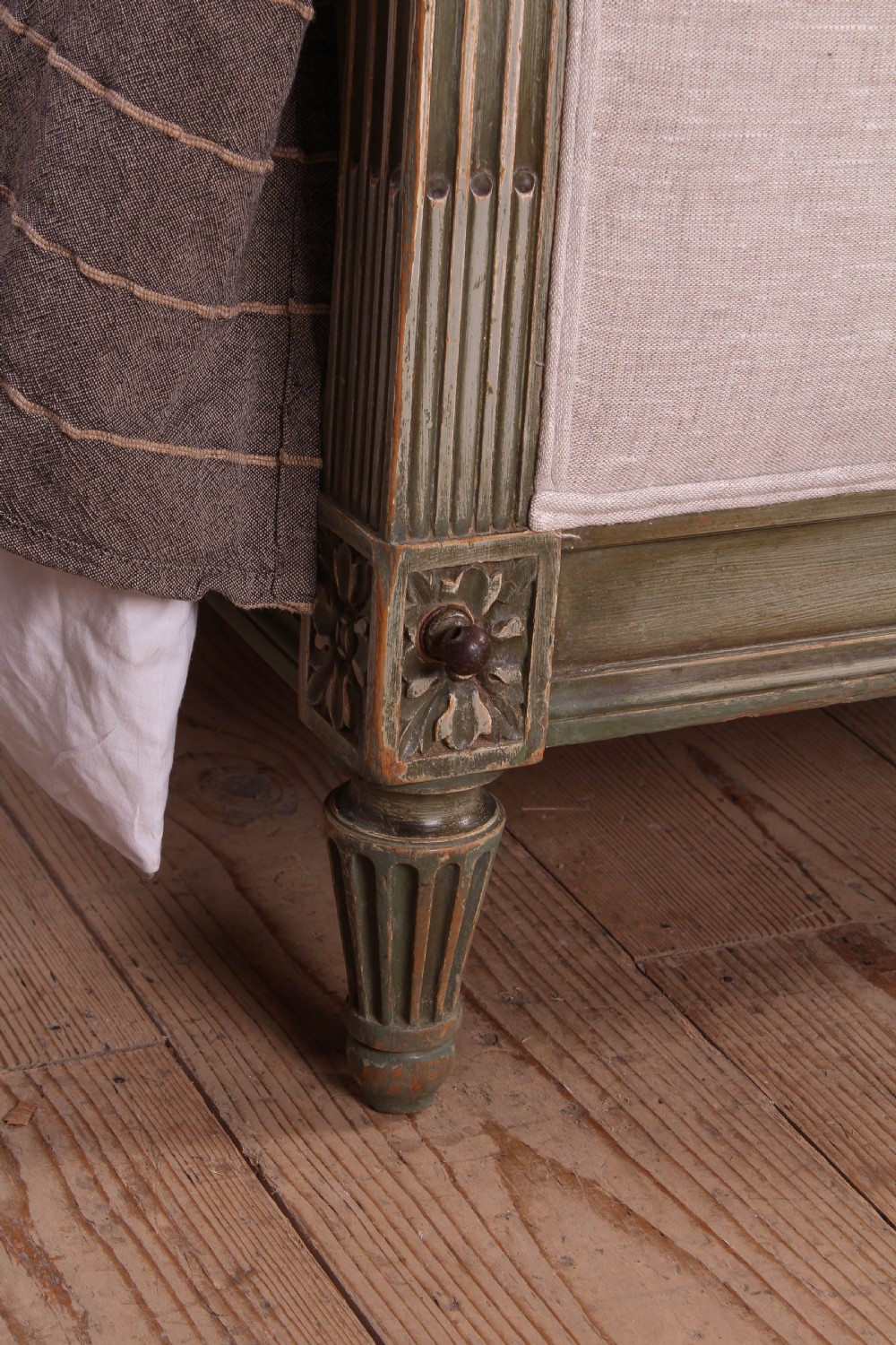 A Louis XVI style French king-size bed frame featuring a muted green painted wooden trim, fluted corner posts, rosettes, and cream linen upholstered panels on the headboard and footboard. View VII