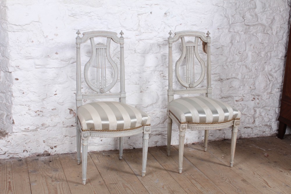 A pair of light grey painted French side chairs featuring lyre-shaped backrests, fluted tapered legs, and cream striped satin upholstery. View II