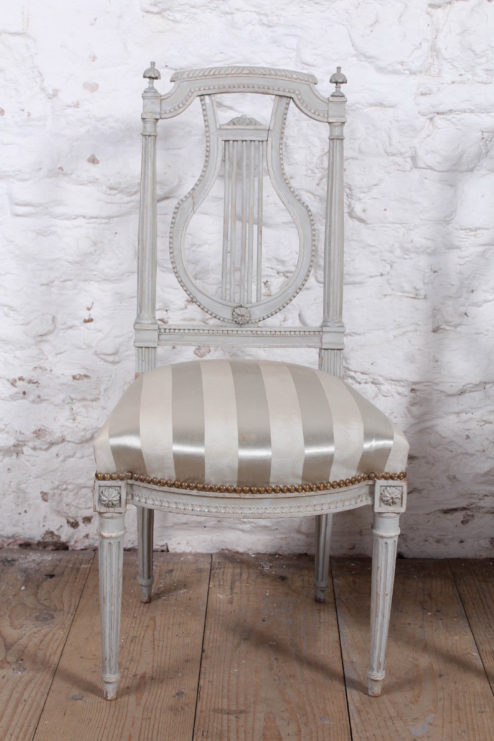 A pair of light grey painted French side chairs featuring lyre-shaped backrests, fluted tapered legs, and cream striped satin upholstery. View III