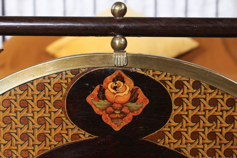 An antique European double bed featuring a dark iron frame, brass top rails, vertical spindles on the headboard, and decorative painted panel inserts on the footboard. View XV