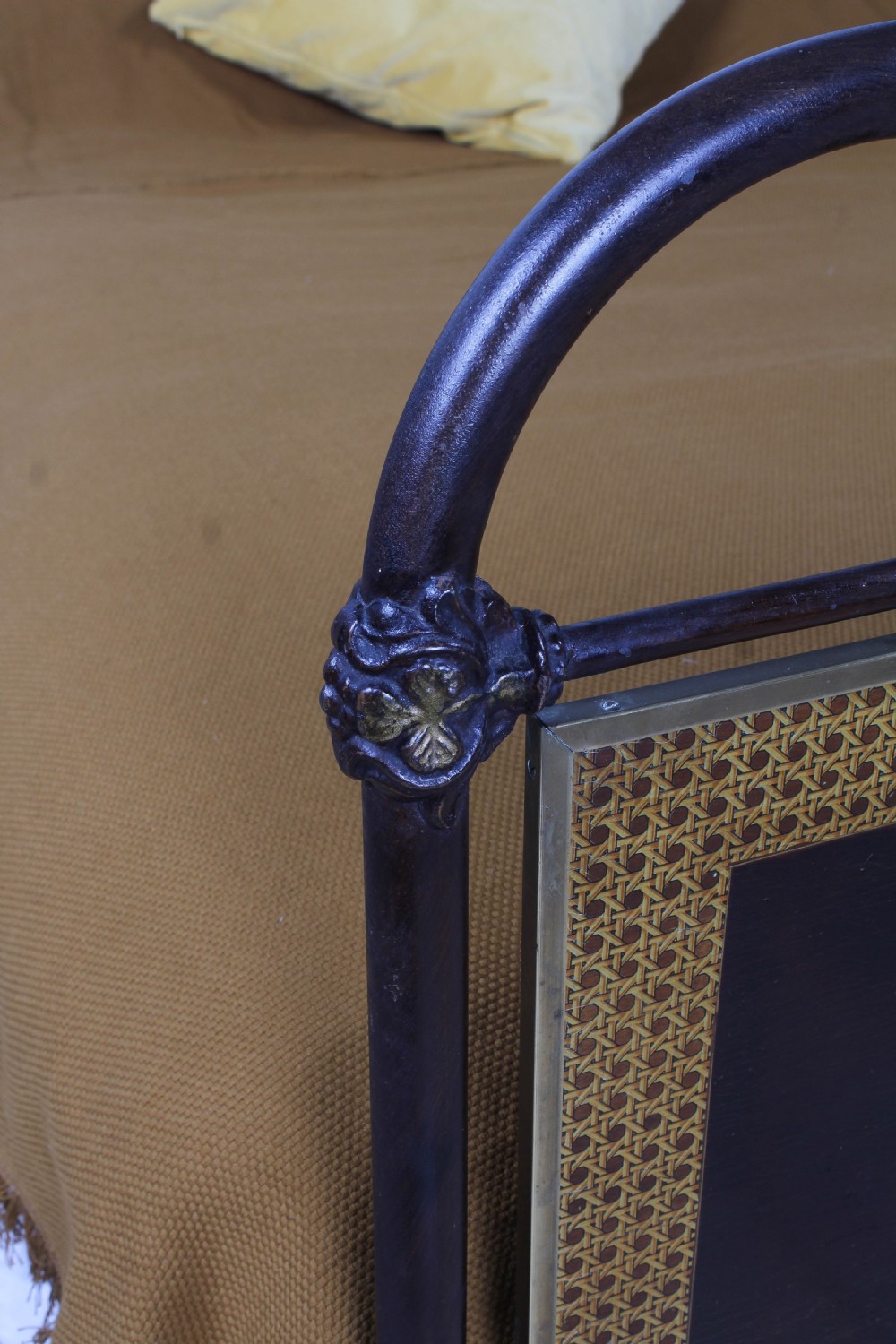 An antique European double bed featuring a dark iron frame, brass top rails, vertical spindles on the headboard, and decorative painted panel inserts on the footboard. View XVI