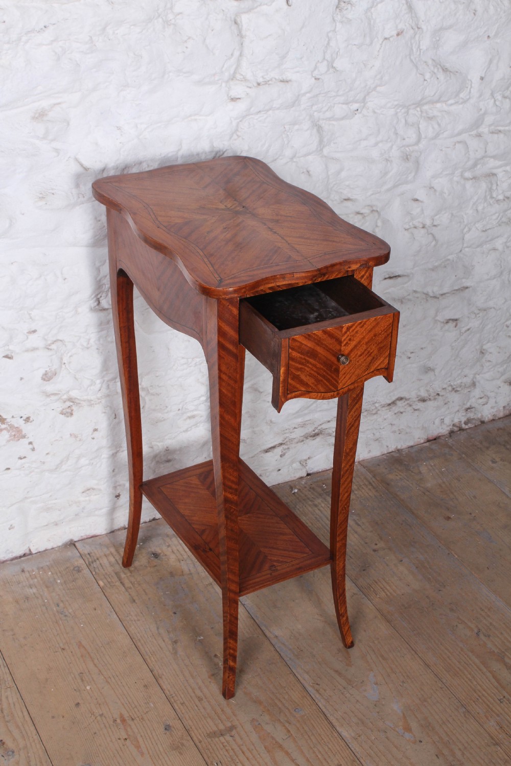 A tall French walnut veneer side table featuring a serpentine top with geometric parquetry inlay, a single front drawer, a lower tier shelf, and slender cabriole legs. View II