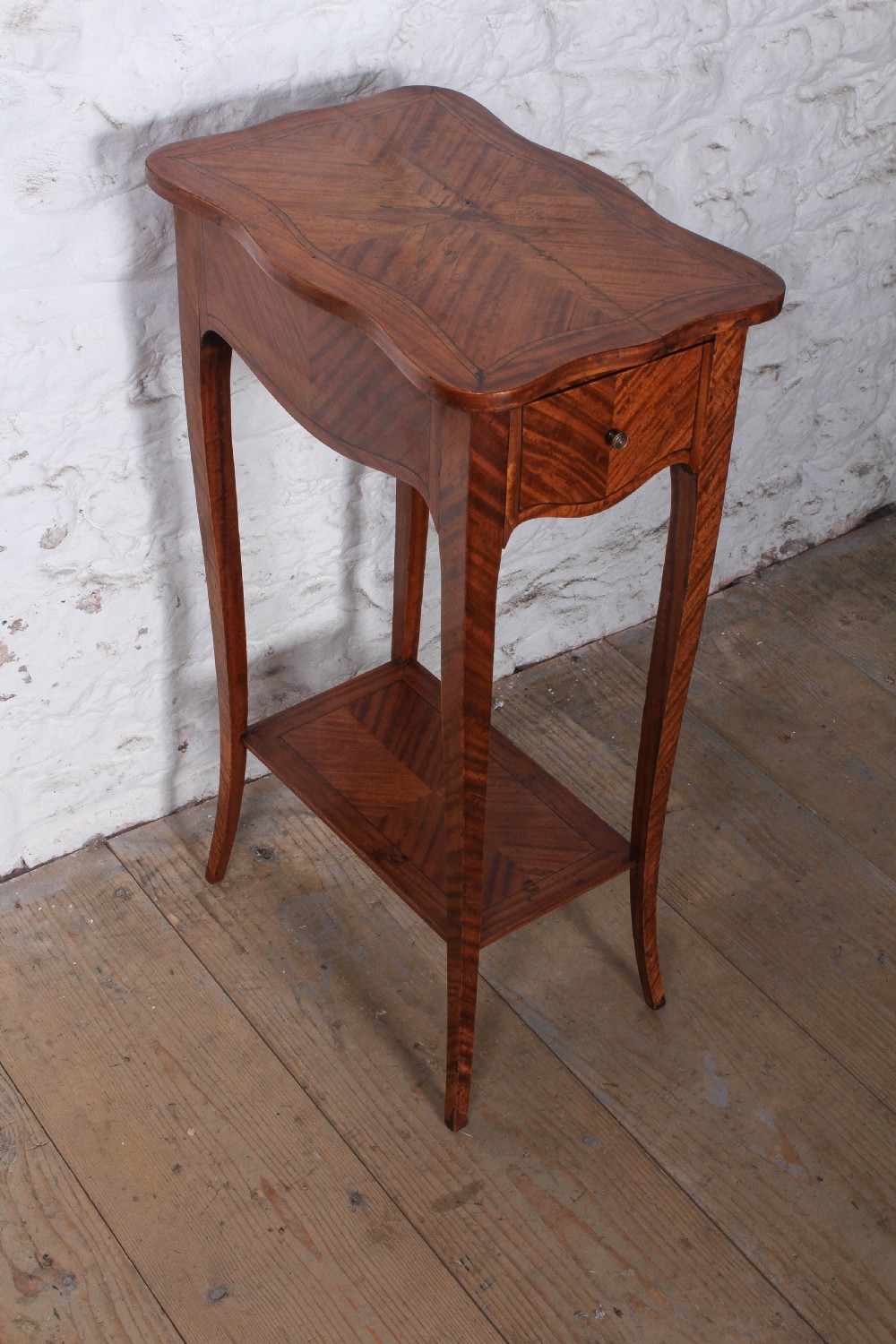 A tall French walnut veneer side table featuring a serpentine top with geometric parquetry inlay, a single front drawer, a lower tier shelf, and slender cabriole legs. View IV